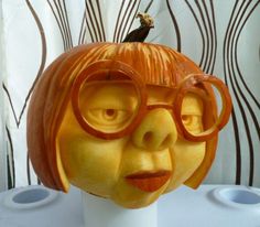 a carved pumpkin with glasses on it's head and a bird perched on top