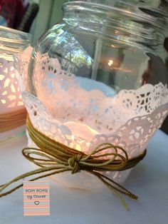 two mason jars with lace doily and twine tied around the lids are sitting on a table