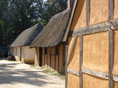 an old village with thatched roofs and wooden buildings on either side of the road