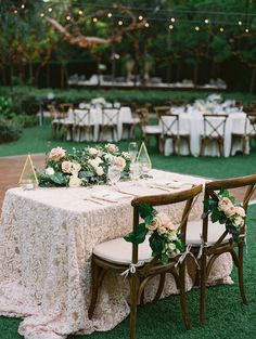 the table is set with flowers and greenery for an outdoor wedding reception at night