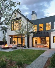 a modern house with an outdoor patio and fire pit in the middle of the yard