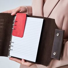 a woman holding a binder with a notepad in it's pocket,