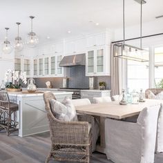 a large open concept kitchen and dining room with hardwood floors, white cabinets, gray countertops, and wooden flooring