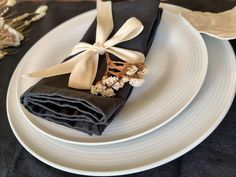 two napkins wrapped in black and white ribbon on top of each other with dried flowers