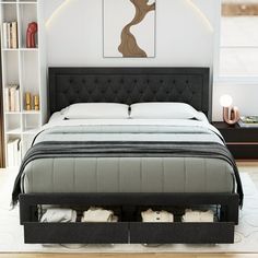 a bed with two drawers underneath it in a white and black bedroom, next to bookshelves