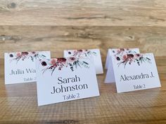 three place cards with flowers on them sitting on a table