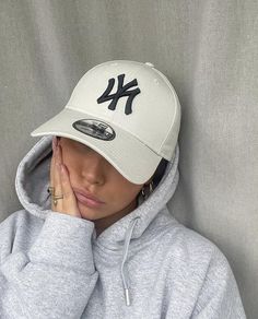 a young woman wearing a new york yankees cap and hoodie with her hands on her face