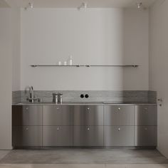 an empty kitchen with stainless steel cabinets and counter tops, along with shelves above the sink