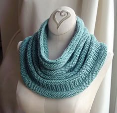 a white mannequin wearing a blue knitted scarf with a heart on it