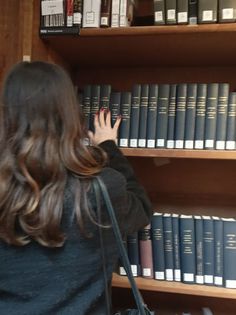 a woman standing in front of bookshelves with her hand on the book shelf