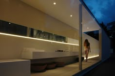 a woman standing in front of a bathroom window at night with her reflection on the wall