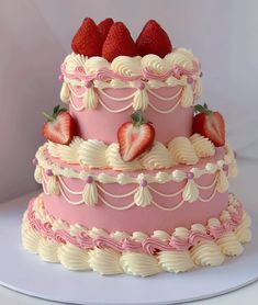 a three tiered cake with strawberries on top and white icing around the edges