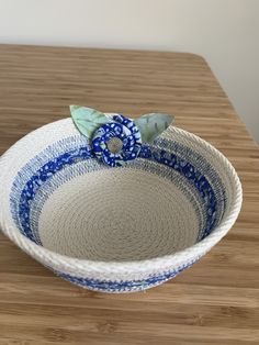 a blue and white bowl sitting on top of a wooden table next to a plant