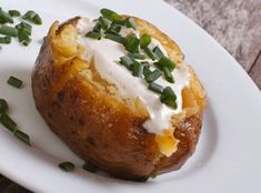 baked potato with sour cream and chives on a white plate