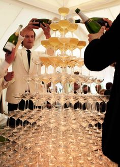 a man in a white suit is pouring champagne into wine goblets at a party