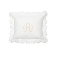 a white pillow with scalloped edges and an embroidered monogram on the front