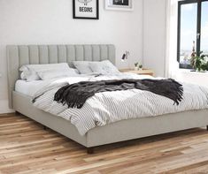 a large bed sitting on top of a hard wood floor next to a window in a bedroom