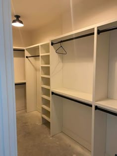 an empty walk in closet with white shelving