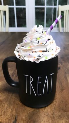 a black coffee mug with white frosting and sprinkles that says treat