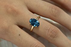 a woman's hand with a ring on it and a blue stone in the middle