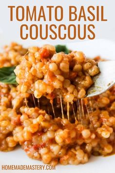 a spoon full of tomato basil couscous on top of a white plate