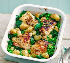 a white dish filled with chicken, potatoes and peas