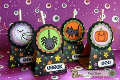 halloween treat bags with stickers on them sitting on a purple tablecloth covered table