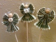 three pinwheels made out of dollar bills on a stick with buttons and bows