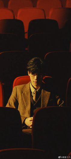 a man in a suit sitting in a theater