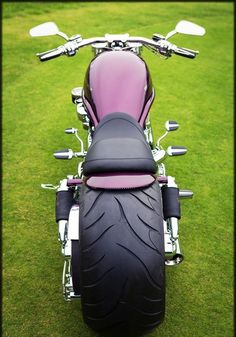 a pink motorcycle parked on top of a lush green field