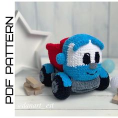 a crocheted blue toy truck sitting on top of a white table next to wooden blocks