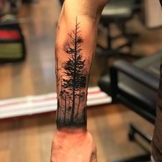 a man's arm with a forest tattoo on it