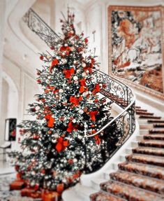 a decorated christmas tree sitting in the middle of a living room next to a stair case