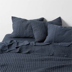 a bed with blue sheets and pillows on it