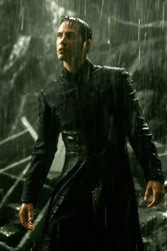 a man standing in the rain with his hand on his hip and looking at something