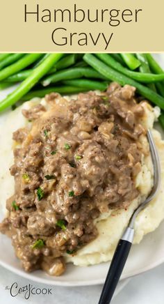 a white plate topped with mashed potatoes covered in gravy and green beans