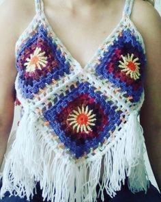 a woman is wearing a crocheted top with fringes and flowers on it