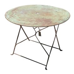 an old table with metal legs and a round top