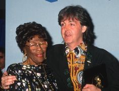 two people standing next to each other with an award in their hands and one person wearing glasses