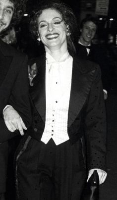 a man and woman in tuxedos are smiling at the camera while standing next to each other