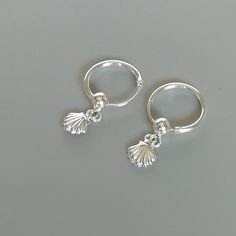 A PAIR of 12 mm sterling silver hoops. Comes with a tiny shell charm. Charm can be used with a neck chain or bracelet. Dimensions: Hoops: 12 x 1 mm Heart: 6 x 6 mm These earrings are made of 925 hypoallergenic sterling silver. All my pieces are sent in a gift box. I can include a personal message from you if needed. You are welcome to contact me at... bhavnakwintra1956@gmail.com More hoops: https://www.etsy.com/your/shops/TheSilverGame/tools/listings/section:26305414 More earrings: https://www.e Beachy Silver Jewelry, Aesthetic Silver Earrings, Silver Shell Jewelry, Cute Silver Hoop Earrings, Silver Shell Earrings, Cute Earrings Silver, Pretty Jewellery Silver, Silver Jewelry Aesthetic Earrings, Cute Silver Jewelry