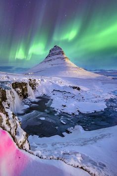 the aurora bore is shining brightly in the sky above snow covered mountains and frozen water