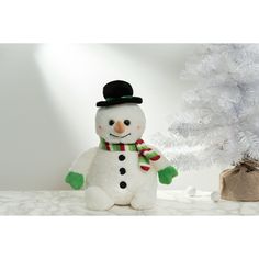 a snowman sitting next to a white christmas tree