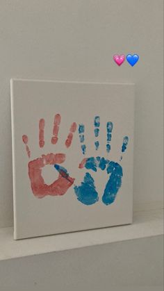 two handprints on a canvas with hearts in the corner and one painted red and blue