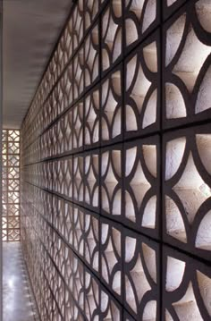 an intricately designed wall in the hallway is lit up by light from behind it