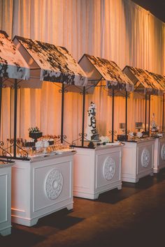 a row of white buffet tables topped with cakes and desserts on top of them