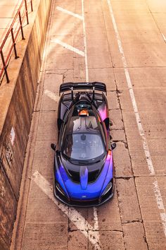 a blue sports car is parked in the middle of an empty parking lot next to a wall