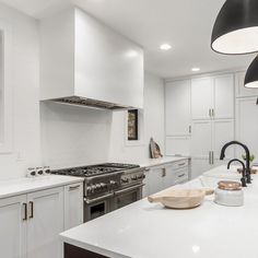 a large kitchen with white cabinets and stainless steel appliances, along with an island in the middle