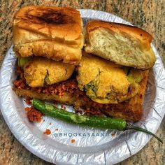 there is a sandwich with meat and vegetables on the paper plate next to some green beans