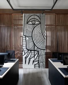 an office with wooden partitions and artwork on the wall, along with computer desks